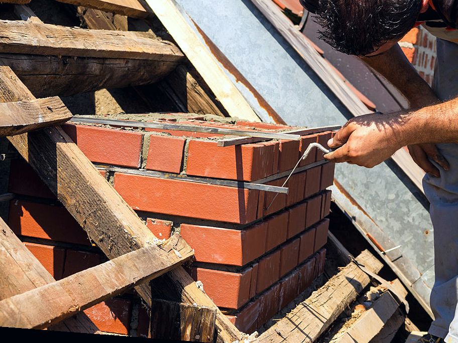 New brick courses climbing on a Boston chimney rebuild